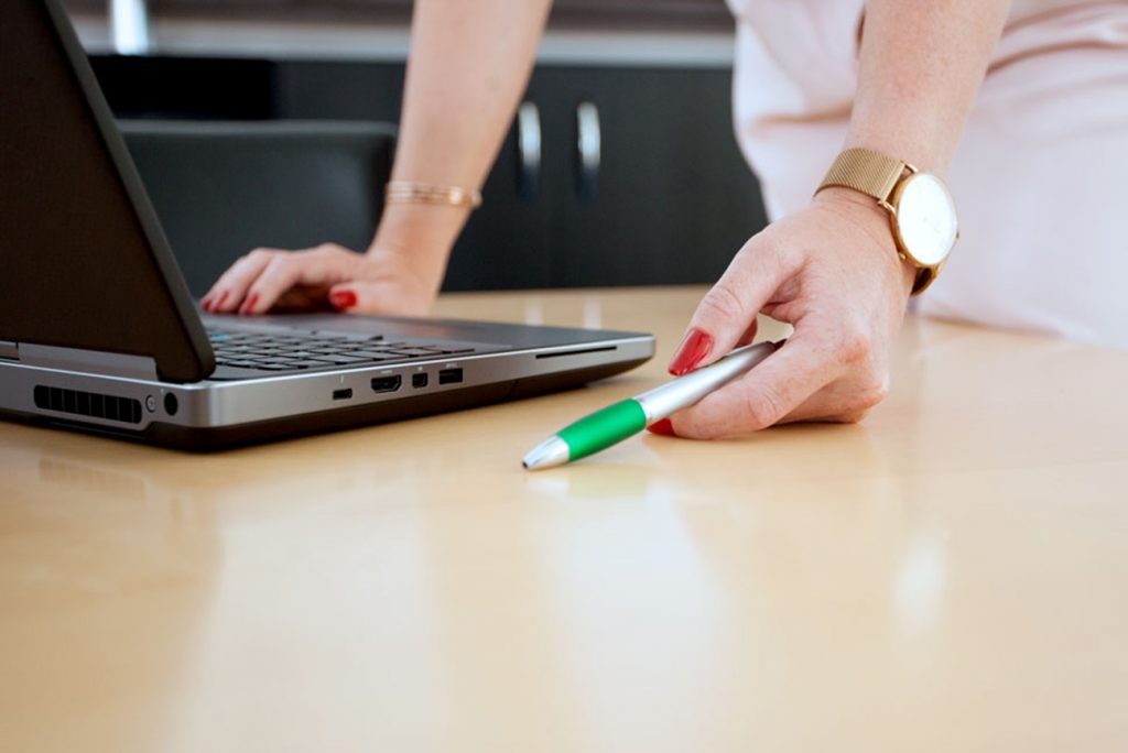 Hände vor einem Laptop mit einem Stift