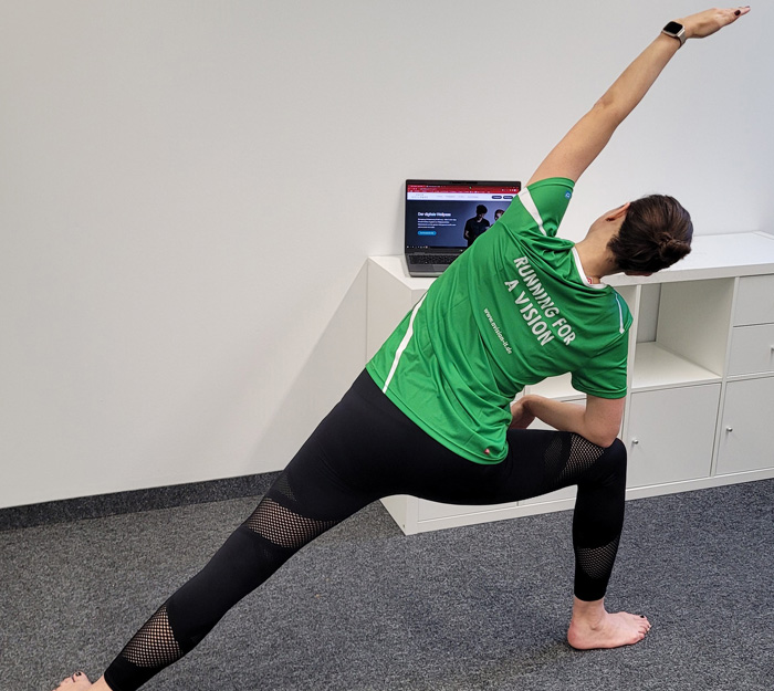 Frau in einem grünen Trikot und schwarzen Leggins macht Yoga